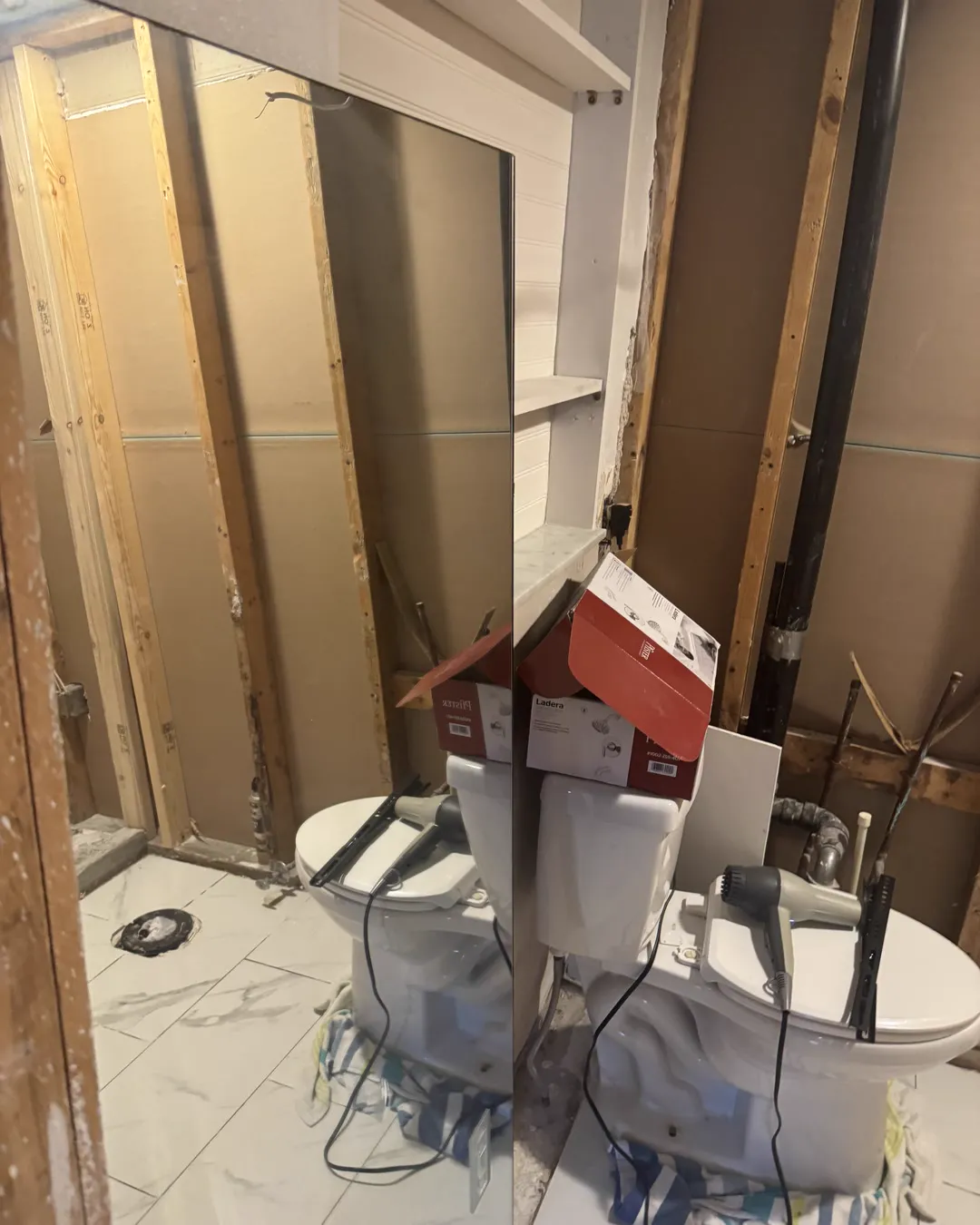 Bathroom demolition with the wall studs exposed and the old floor tile still down