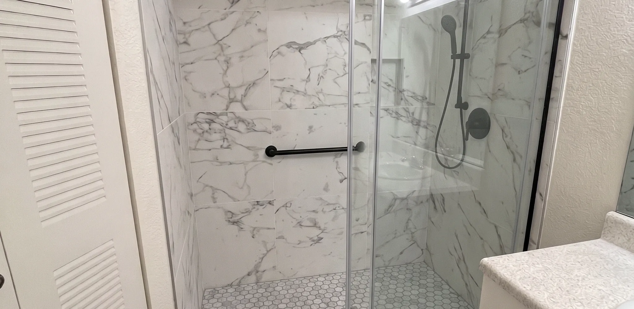 Tiled walk-in shower with a low curb and a sliding glass door