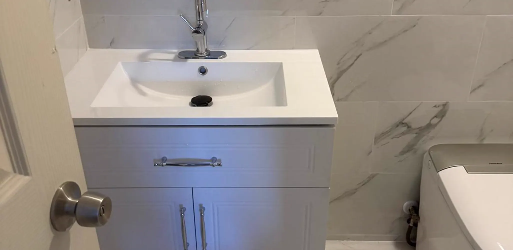 Compact bathroom finished with a vanity and tile up the wall