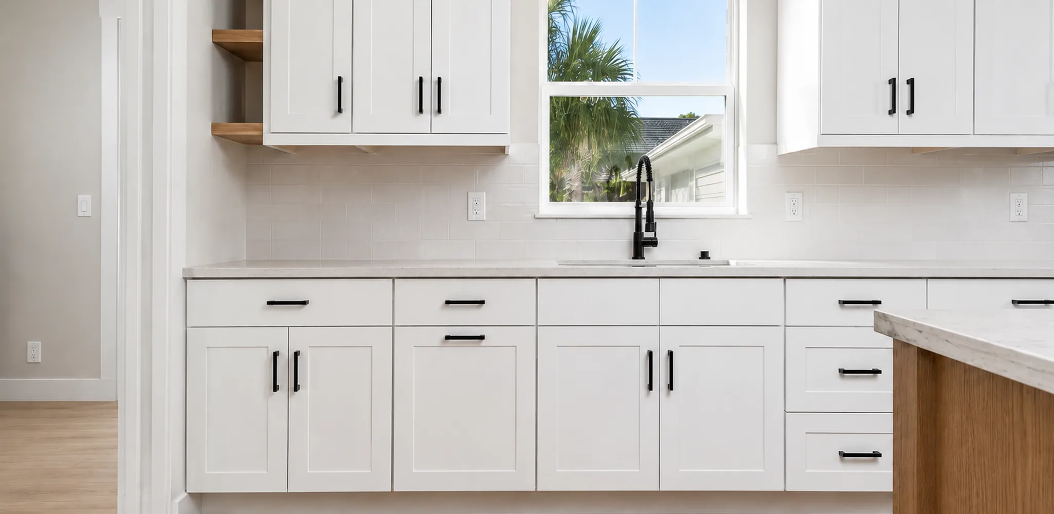 White shaker cabinets with black handles around a kitchen sink, cabinet installation