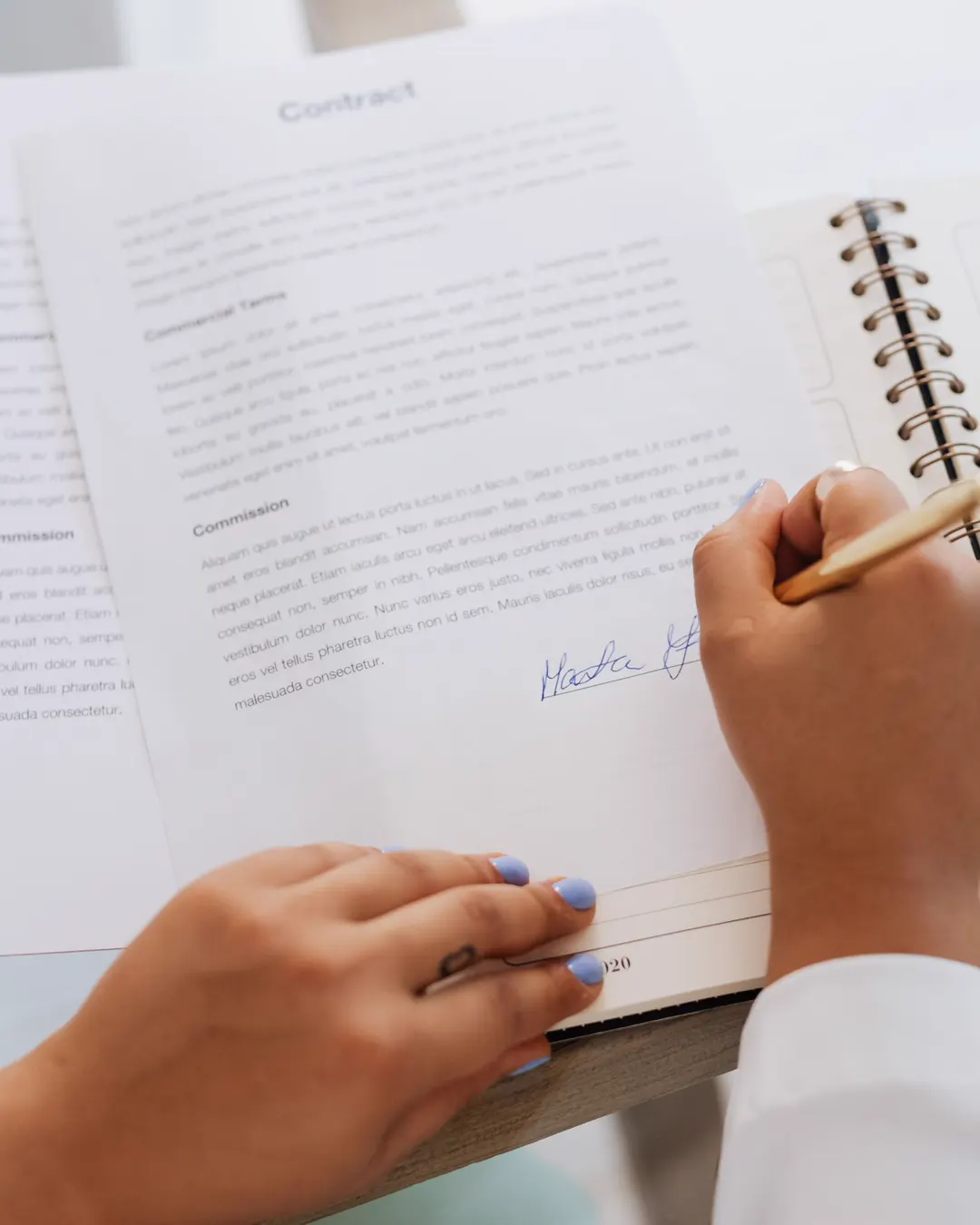 Two hands signing a written agreement on a desk with a pen, the legal terms of Maplex Services