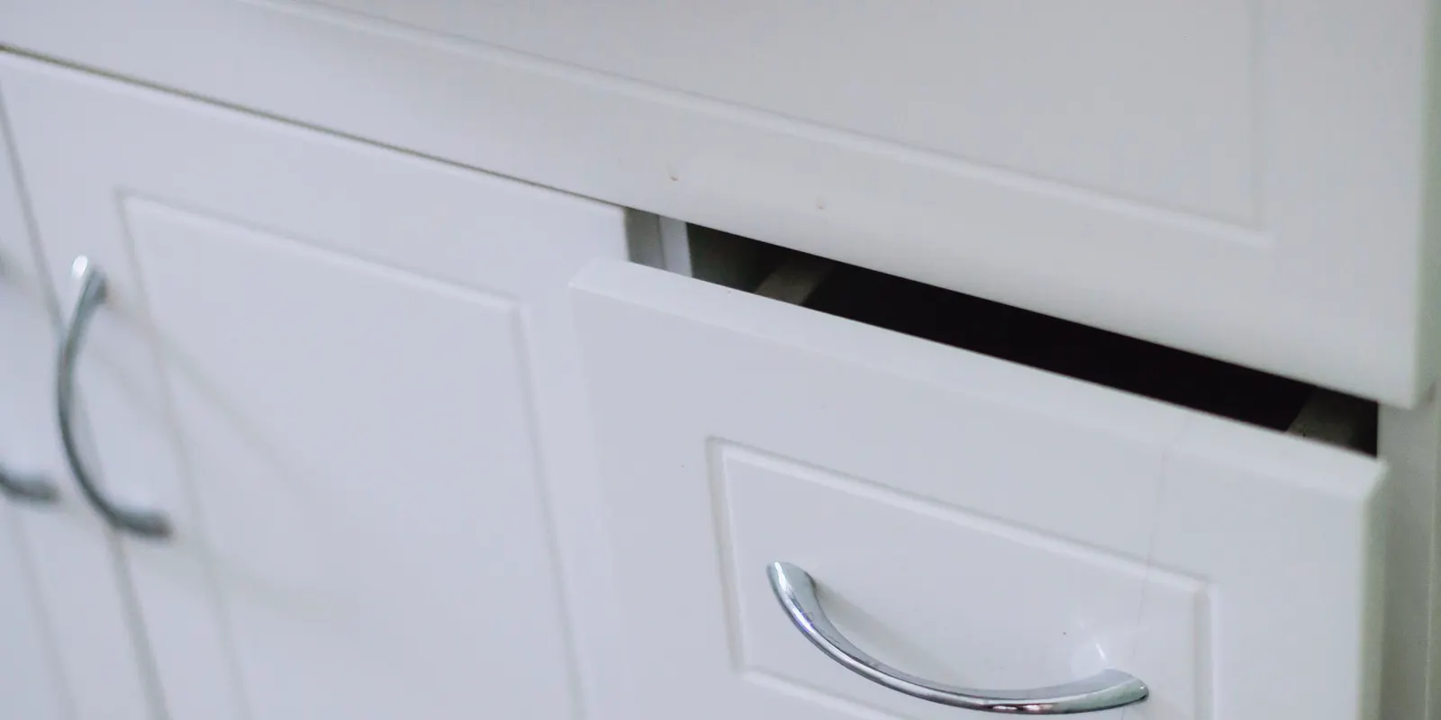 A close-up of a white bathroom cabinet with a drawer under a sink, bathroom vanity installation
