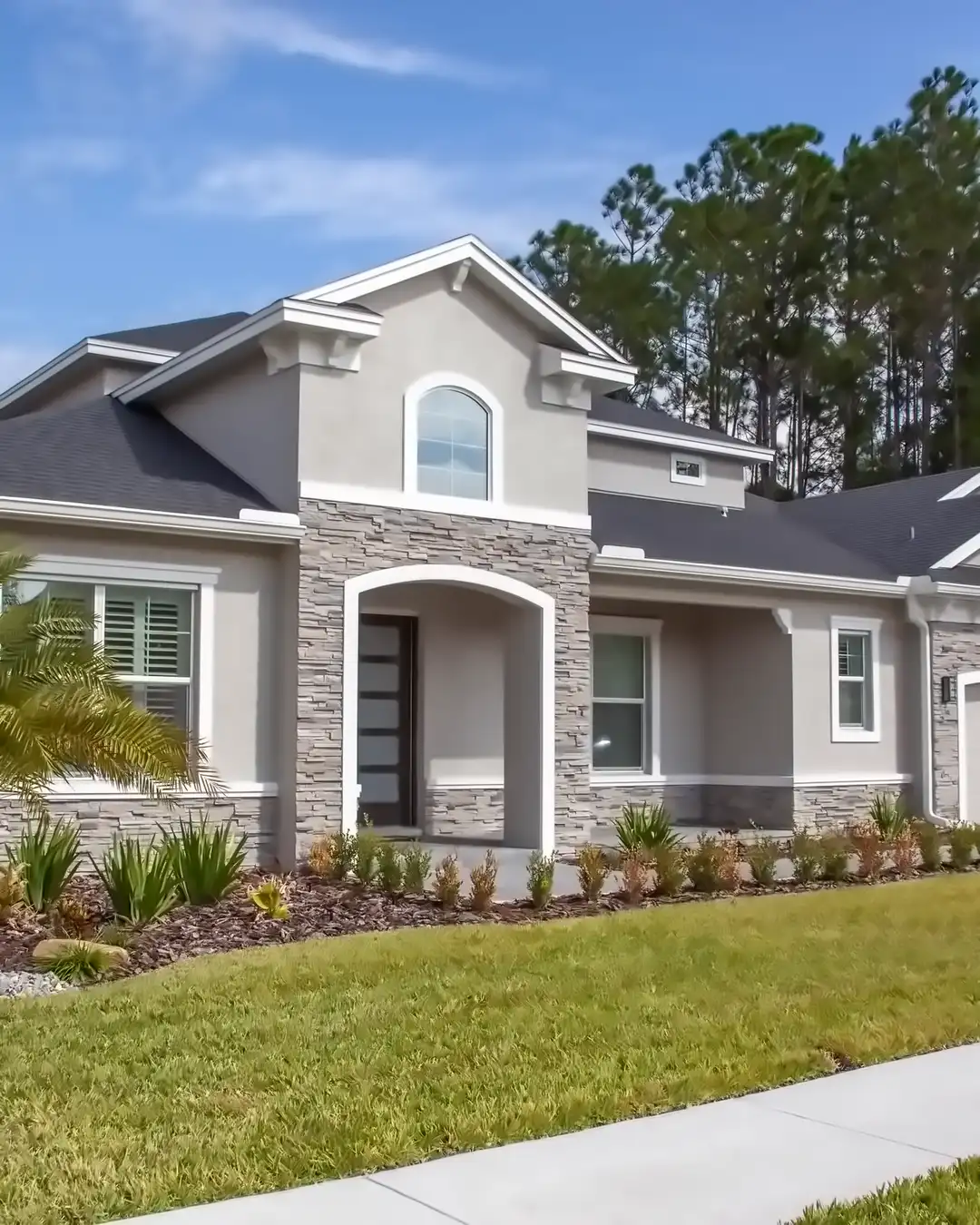 A stucco house with a stone trimmed entry, new windows and a concrete walk, the kind of house home remodeling in Brandon, FL often starts with
