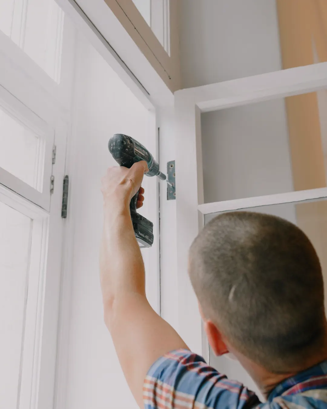 A craftsman seen from behind assembling a cabinet with a cordless screwdriver, cabinet installation cost