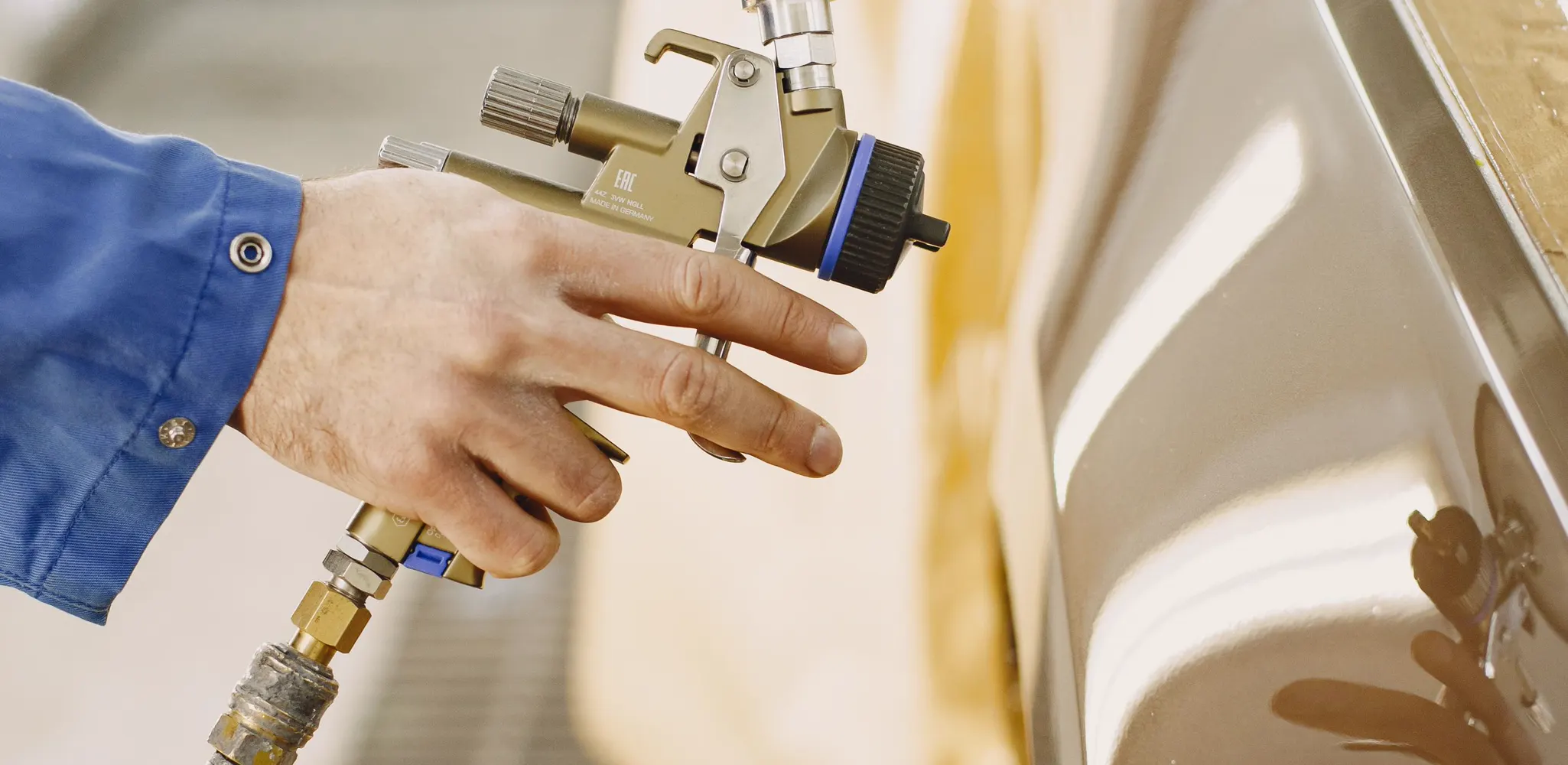 A spray gun finishing a cabinet door laid flat, cabinet painting