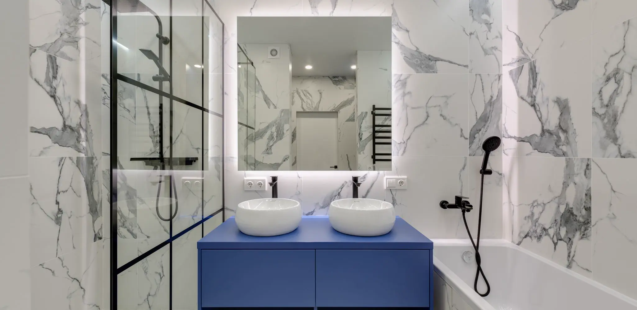 A bathroom with marble walls, two sinks and a glass shower, bathroom remodeling