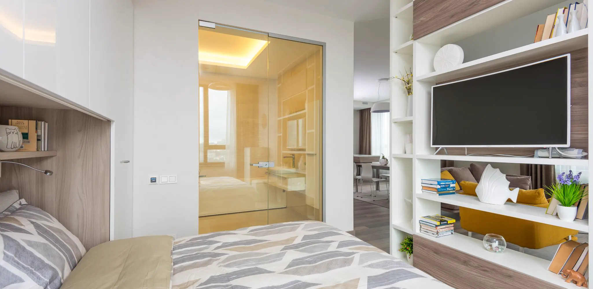 A small bedroom open to a living room behind a shelf, garage conversion