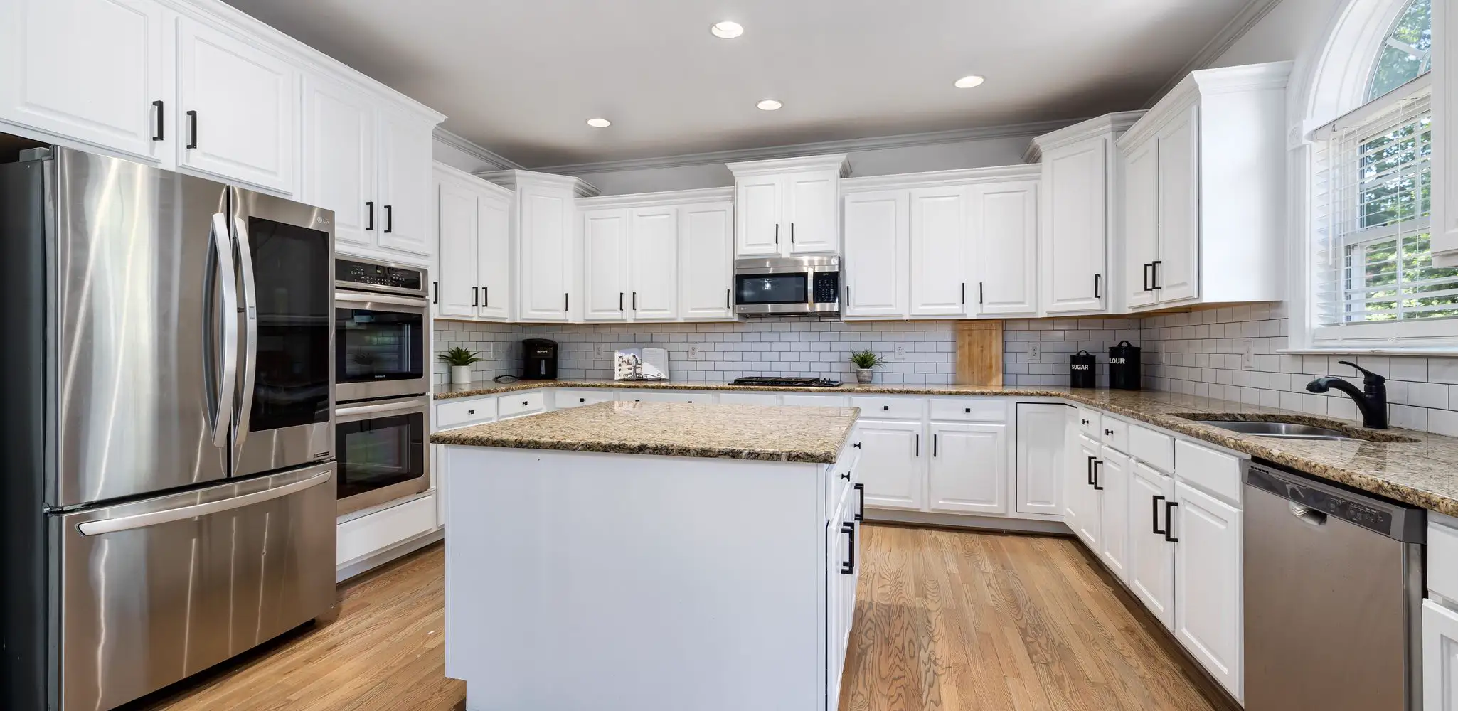 A kitchen with white cabinets, granite counters and a steel range, kitchen remodeling