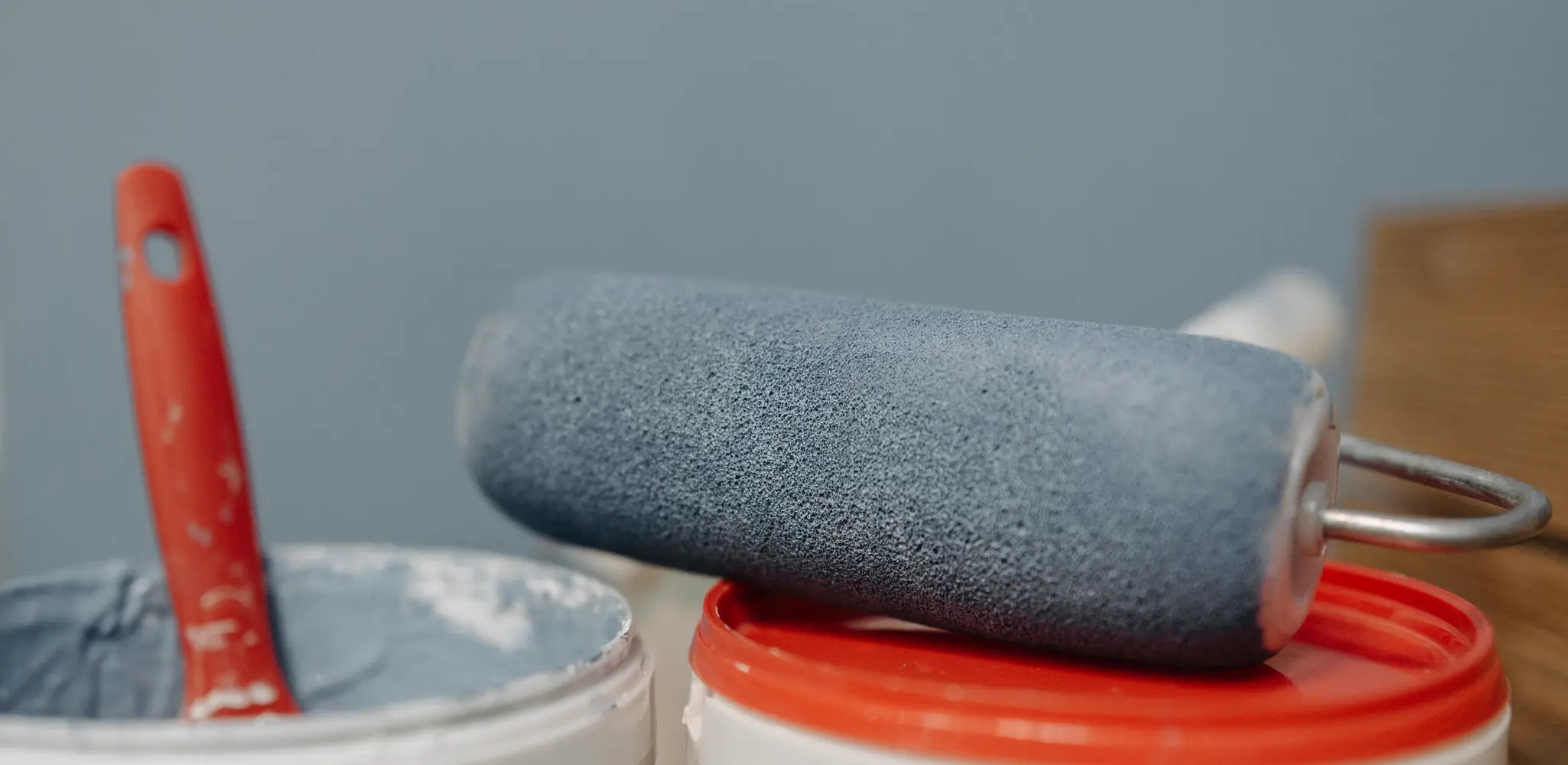 A paint roller resting on paint buckets, interior and exterior painting