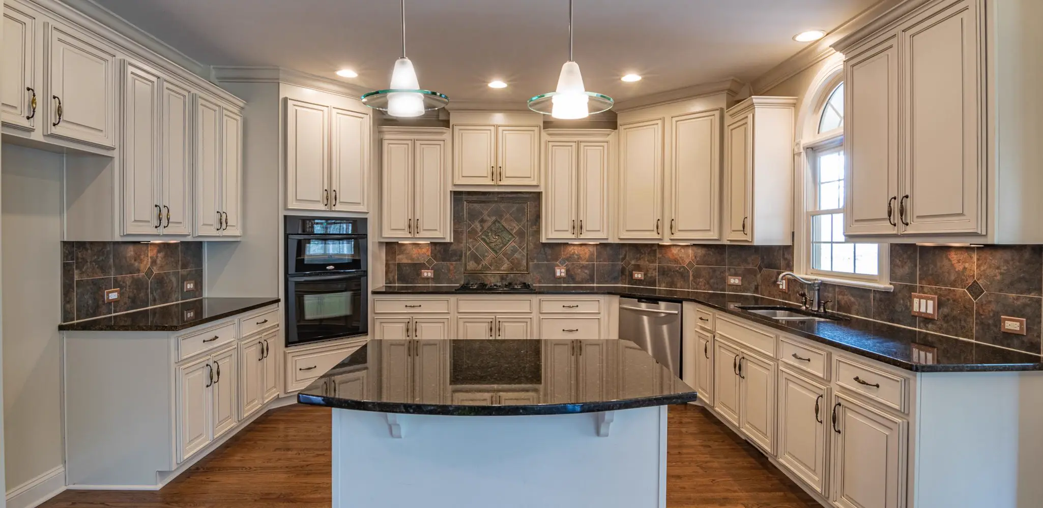 A kitchen with white cabinets, granite counters and wood floors, kitchen remodeling