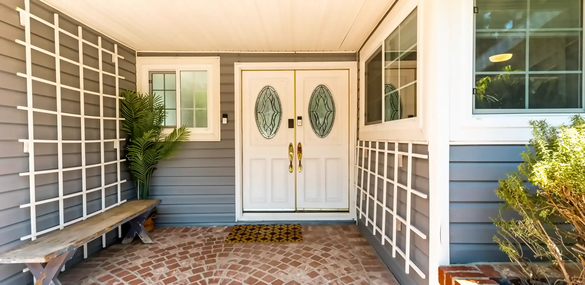 A porch with double doors and a brick floor, exterior and front of house