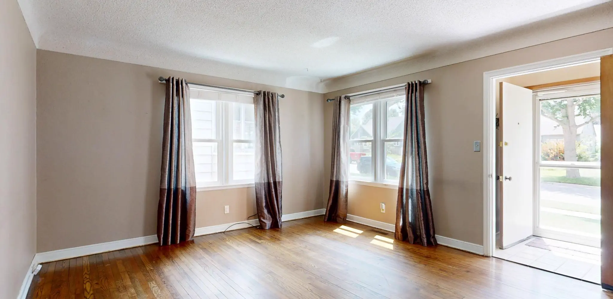 An empty living room with hardwood floors and an open plan, flooring installation