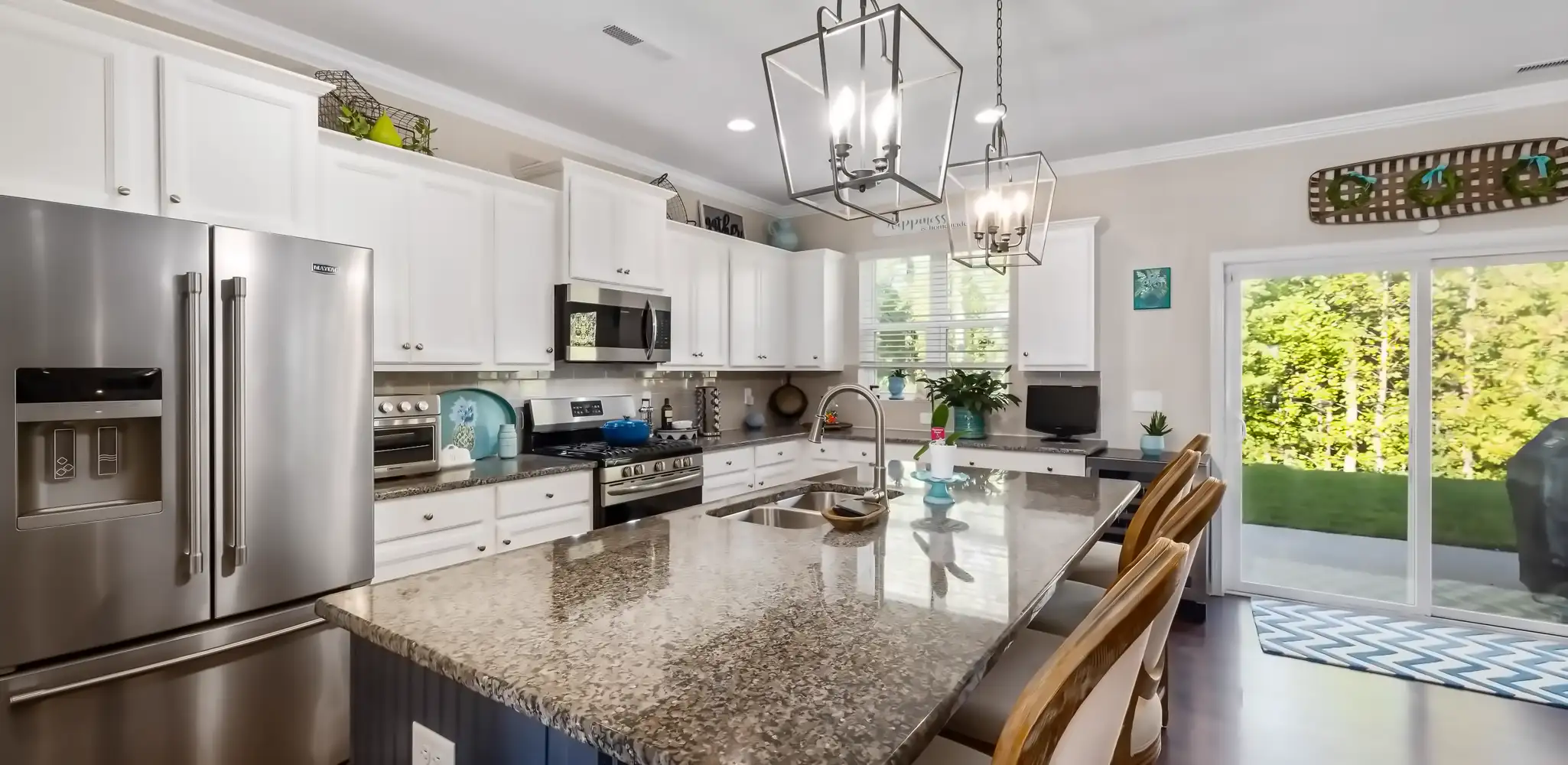 A kitchen with a granite island and stainless steel appliances, kitchen remodeling
