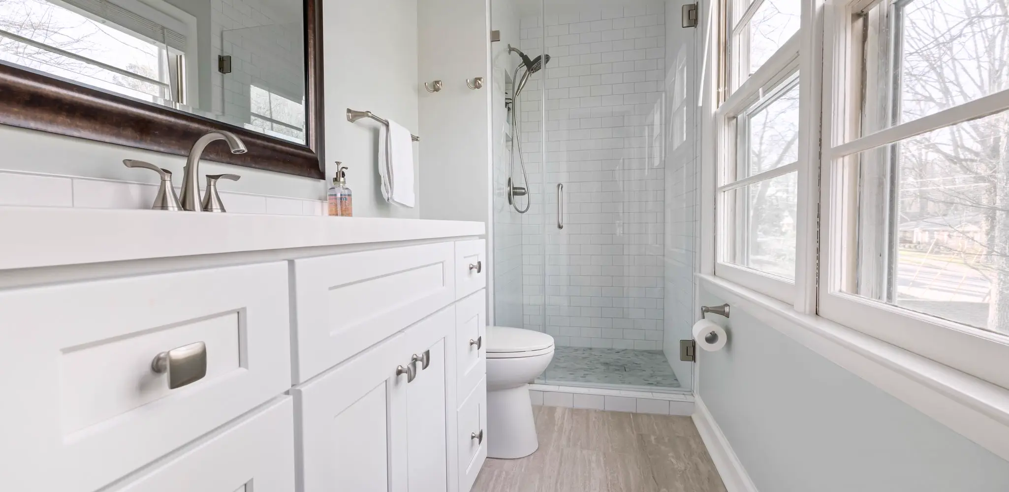 A white vanity and a glass shower in a bright bathroom, bathroom remodeling
