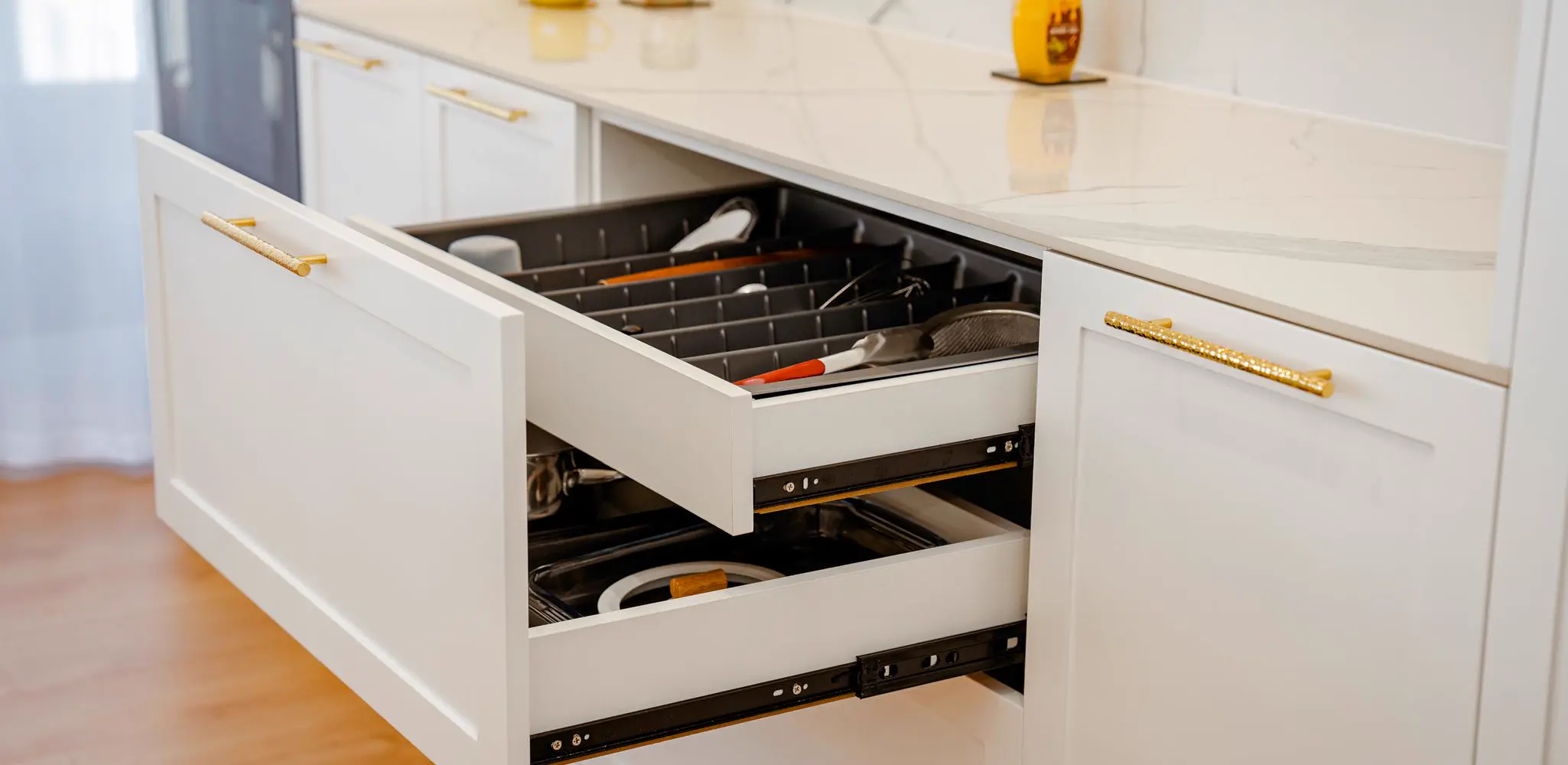 An open white kitchen drawer on a marble counter, cabinet installation