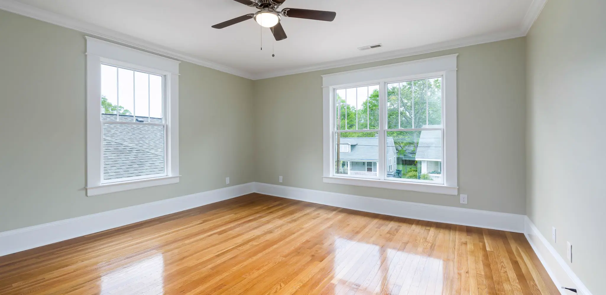 An empty room with wood floors, big windows and a ceiling fan, flooring installation