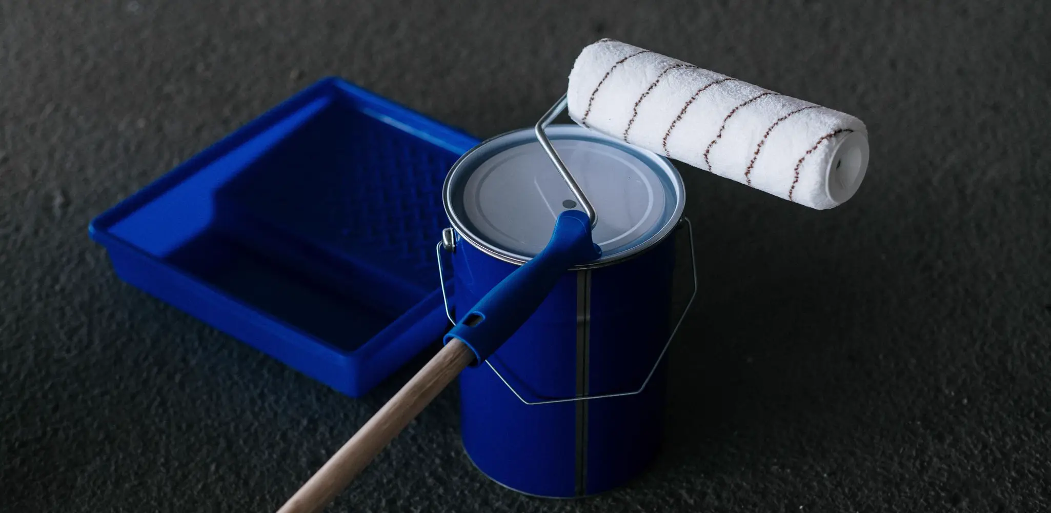 A paint can, a roller and a tray on the floor, interior and exterior painting