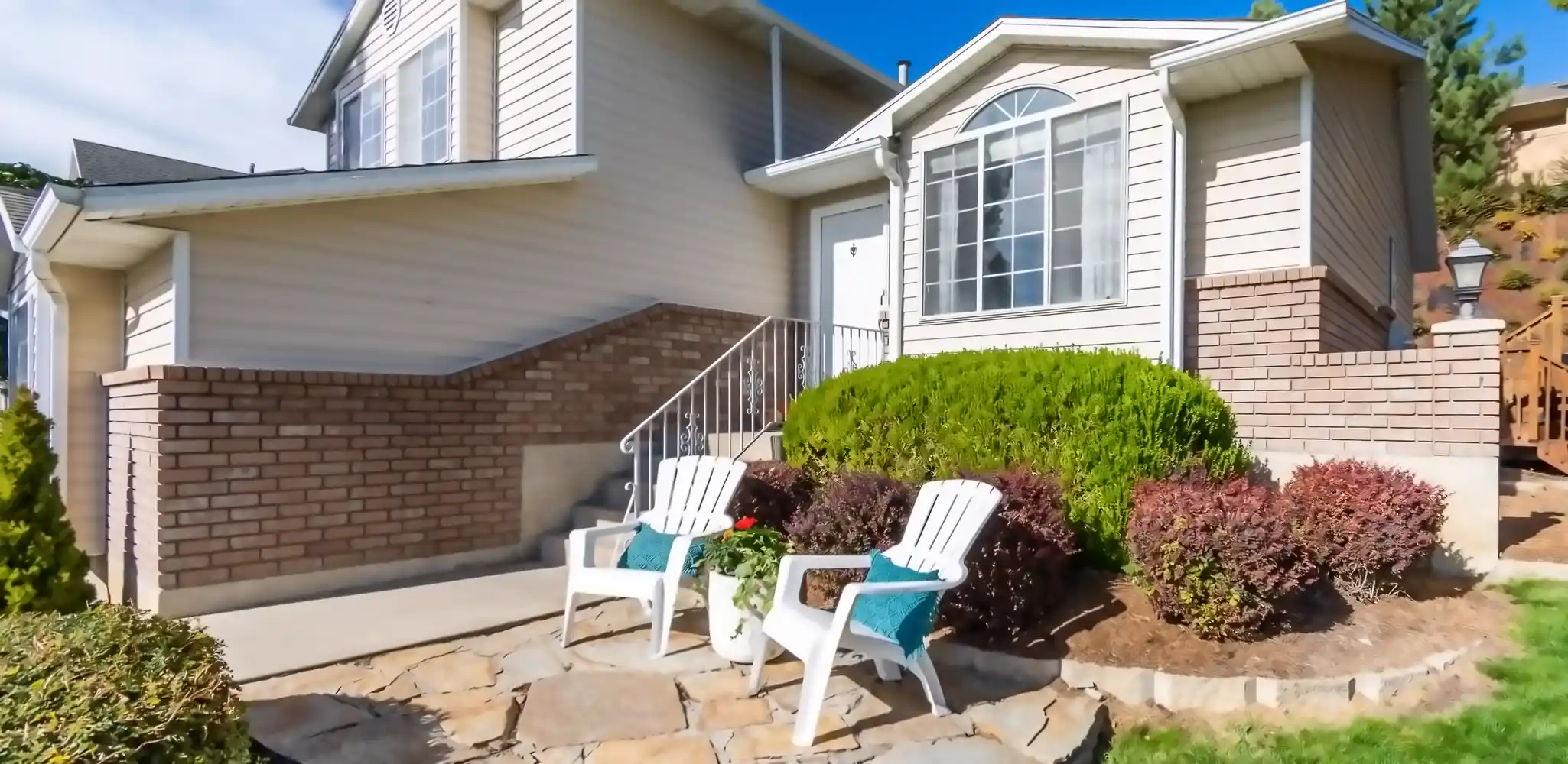 A house with a front porch and seating in bright light, exterior and front of house