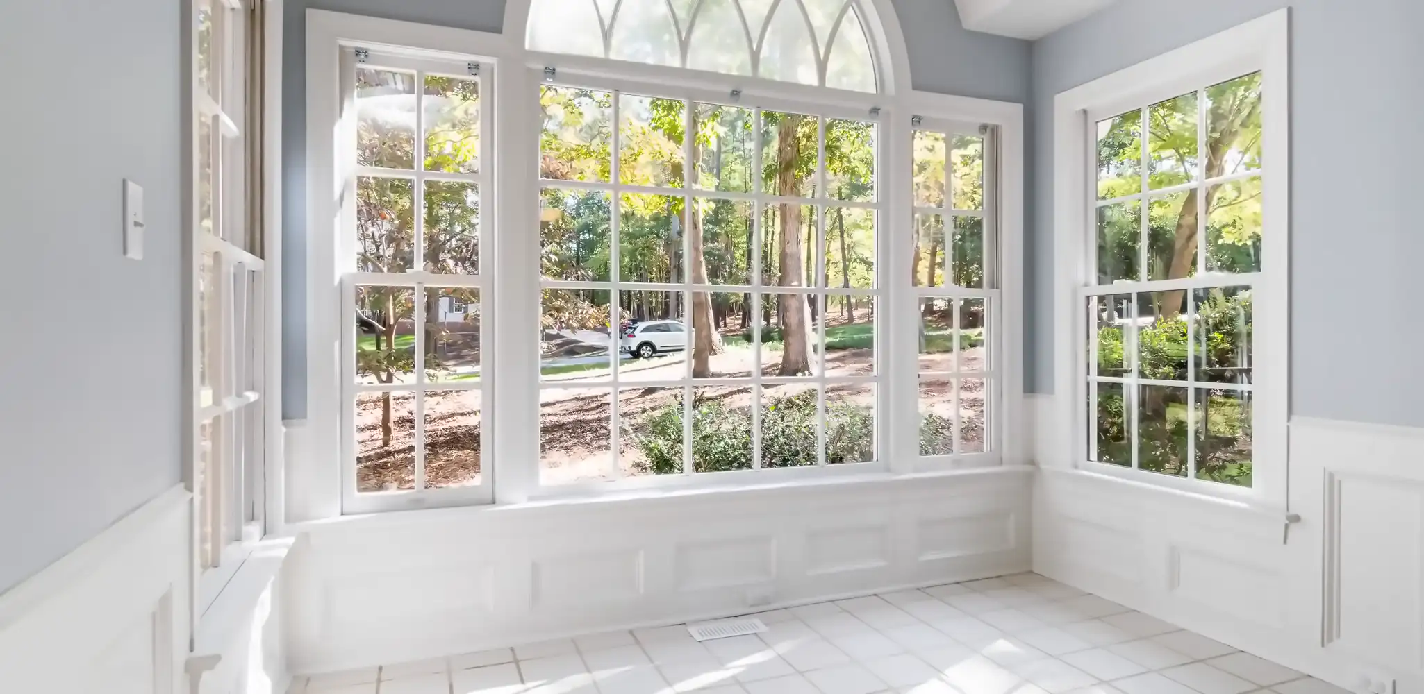A sunroom with large glass windows facing the yard, home additions