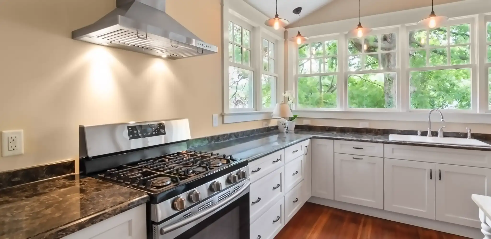 A kitchen with a gas range, white cabinets and a window, kitchen remodeling