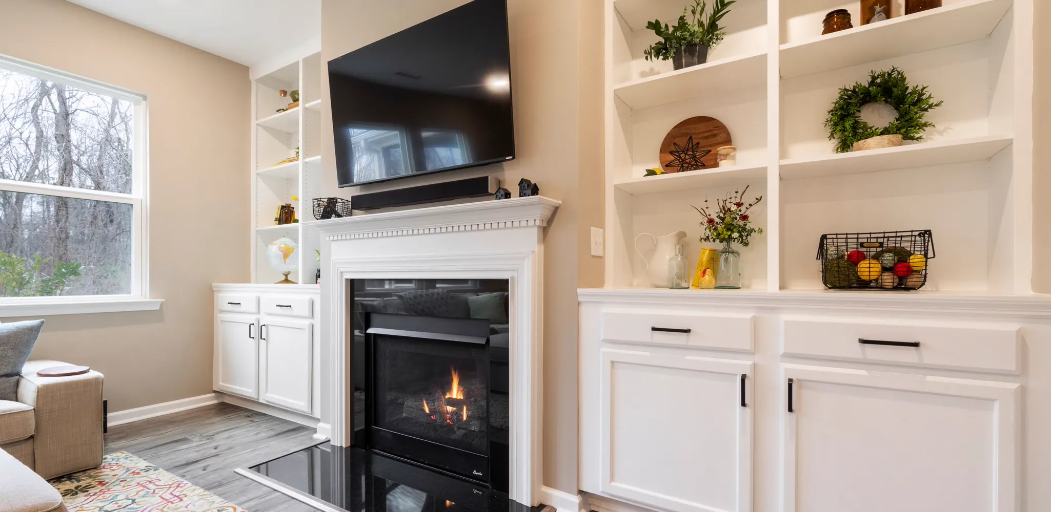 A living room fireplace with white built-in shelving on both sides, the finished side of a built-in job