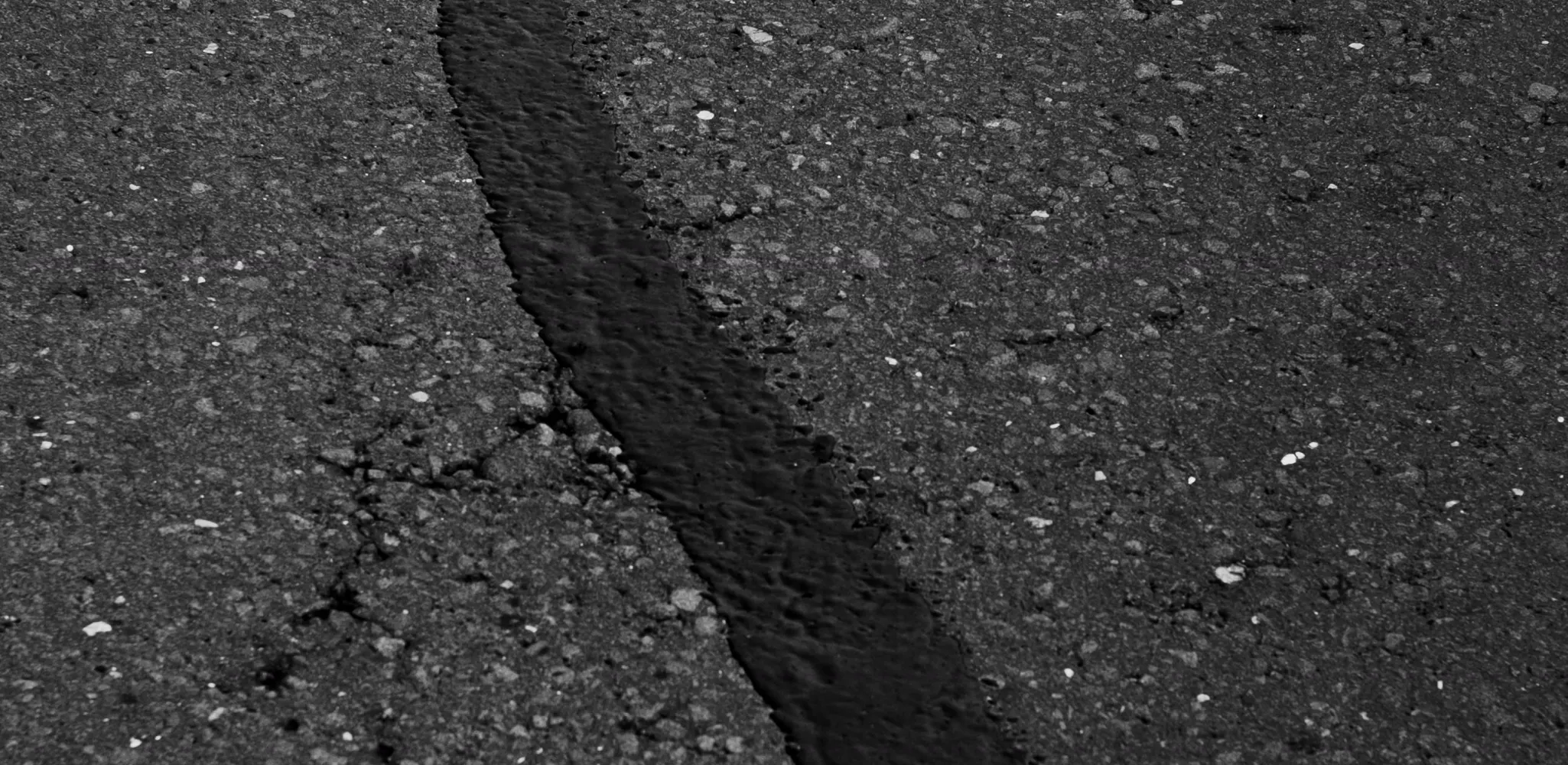 Close up of a cracked asphalt surface, driveway repair
