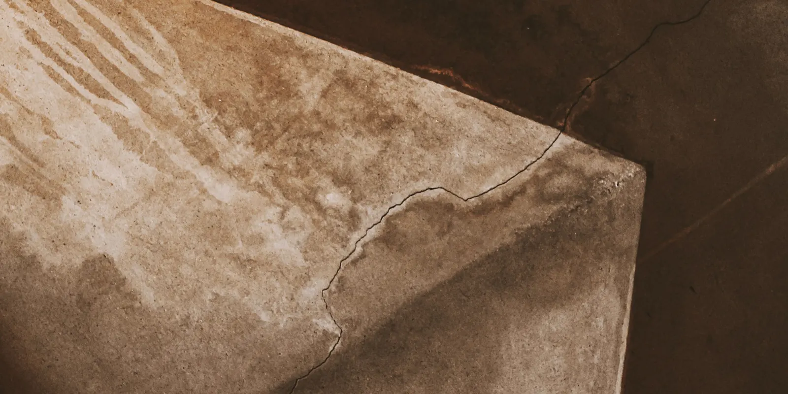 A cracked and stained concrete surface before repair, drywall repair