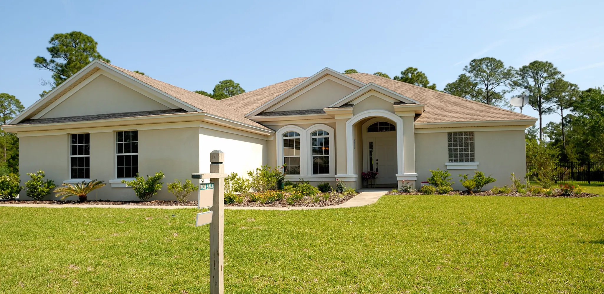 A one story stucco house with a green lawn, exterior remodel cost