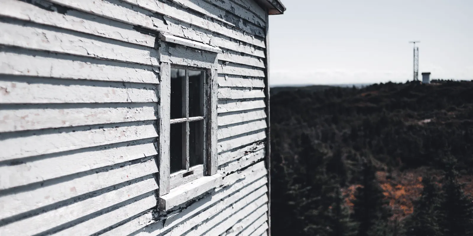 A weathered wooden house wall with peeling paint, exterior remodel cost