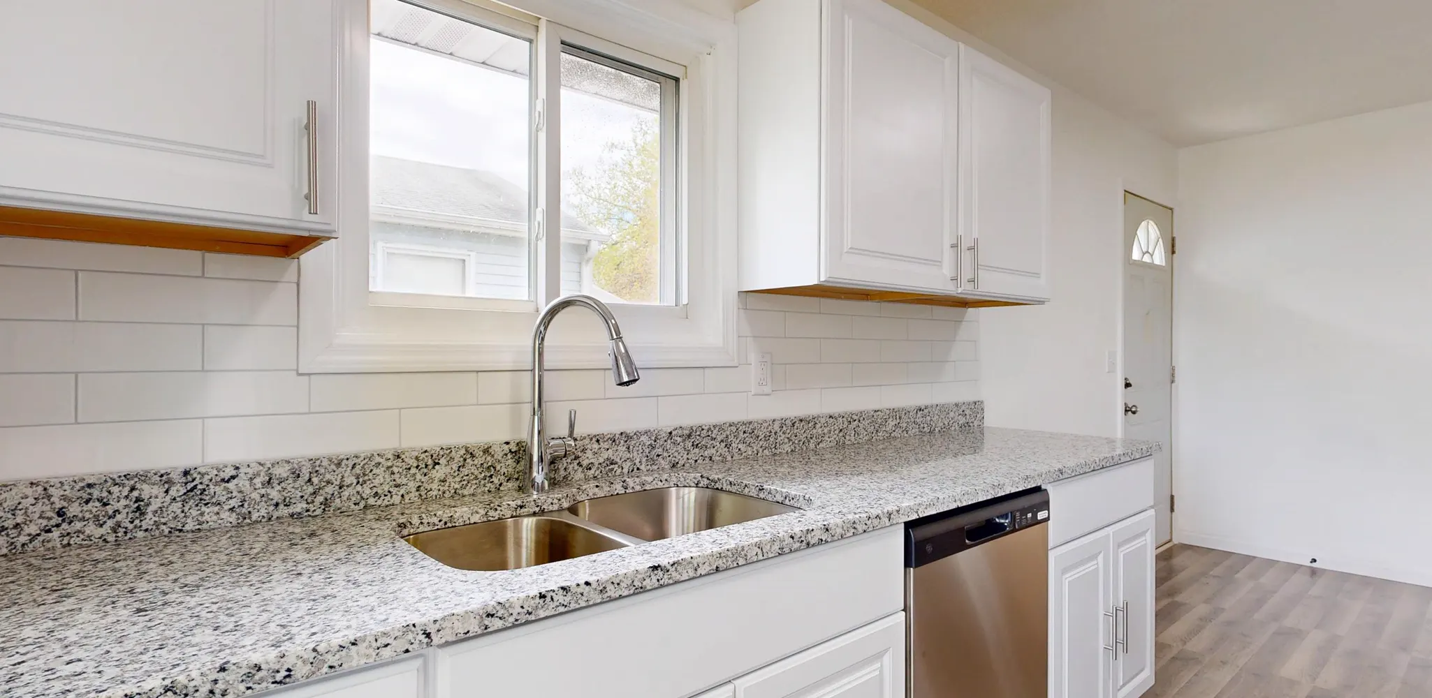 A white kitchen with a plank floor running under the cabinets, flooring cost