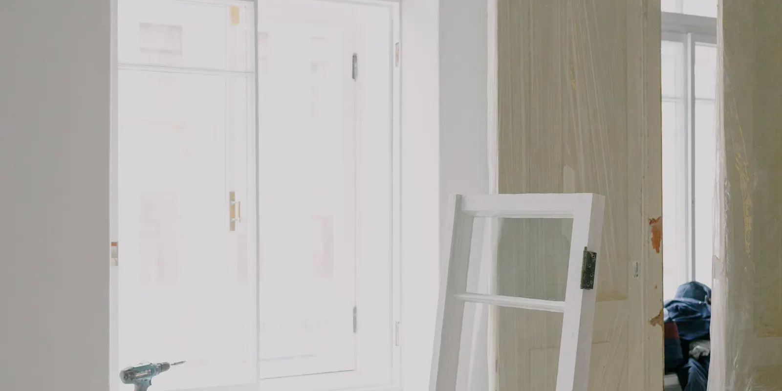 A window frame on the floor next to wooden doors during a renovation, front door replacement