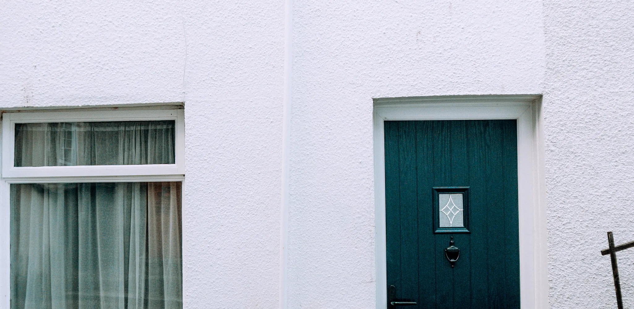 A white house wall with a dark front door, front door replacement