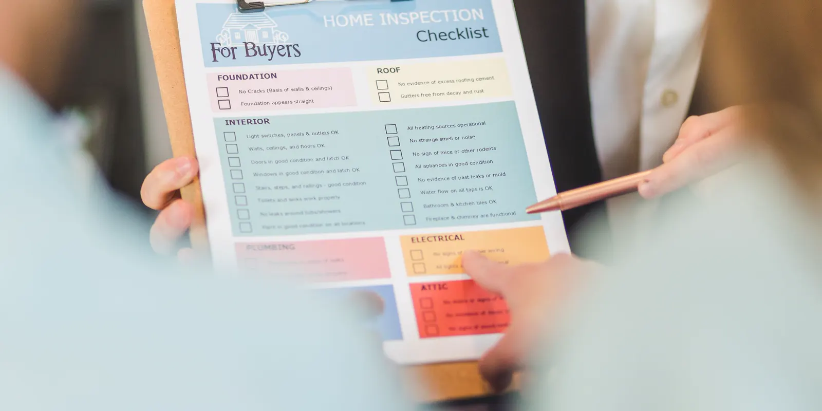 Hands holding a home inspection checklist on a clipboard, front of house remodel