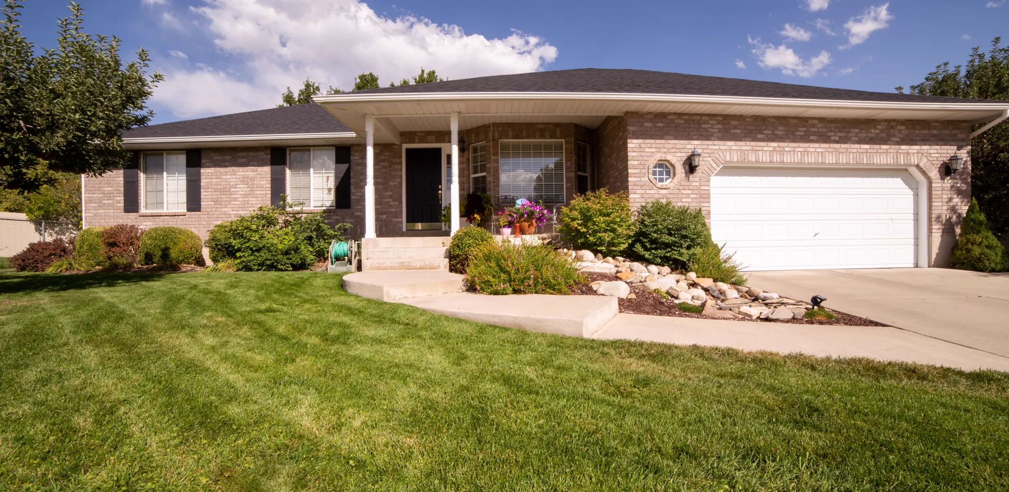 A one story house with a clean front and a paved walk, front of house remodel