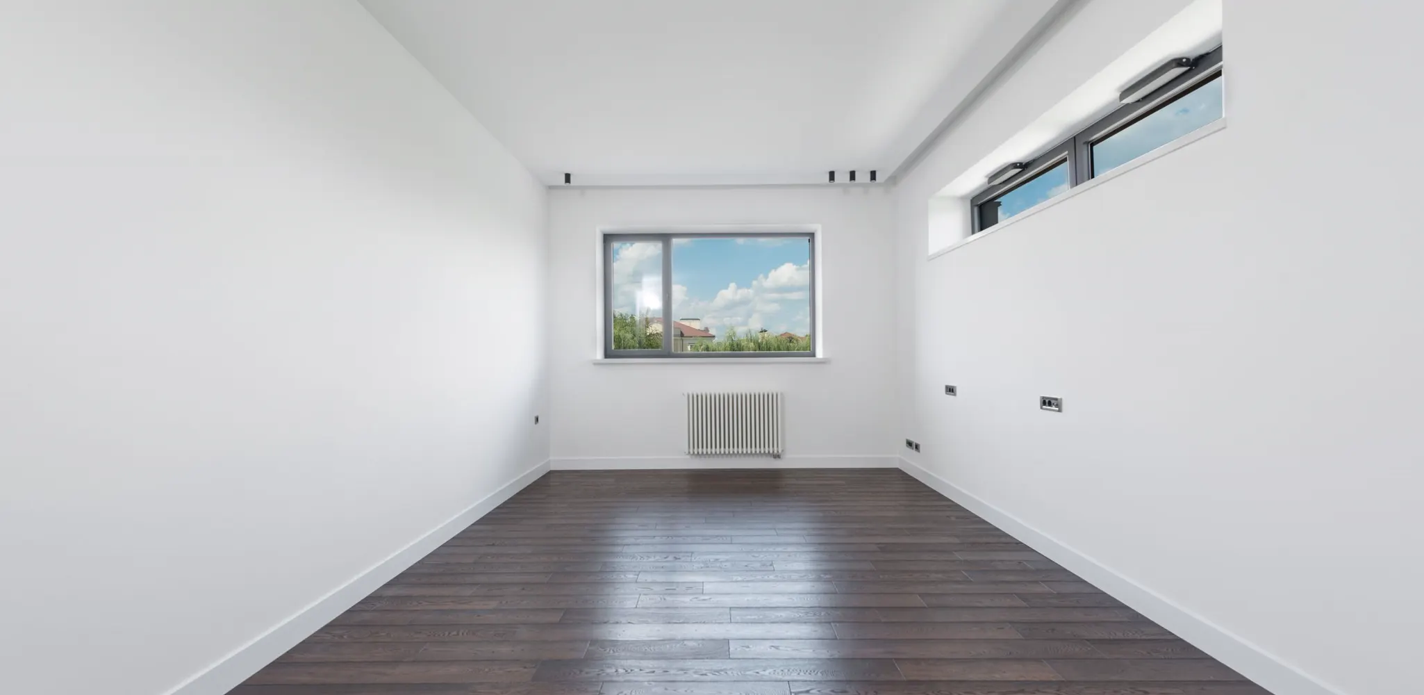 A bright empty room with new flooring and a large window, the finished side of a garage conversion