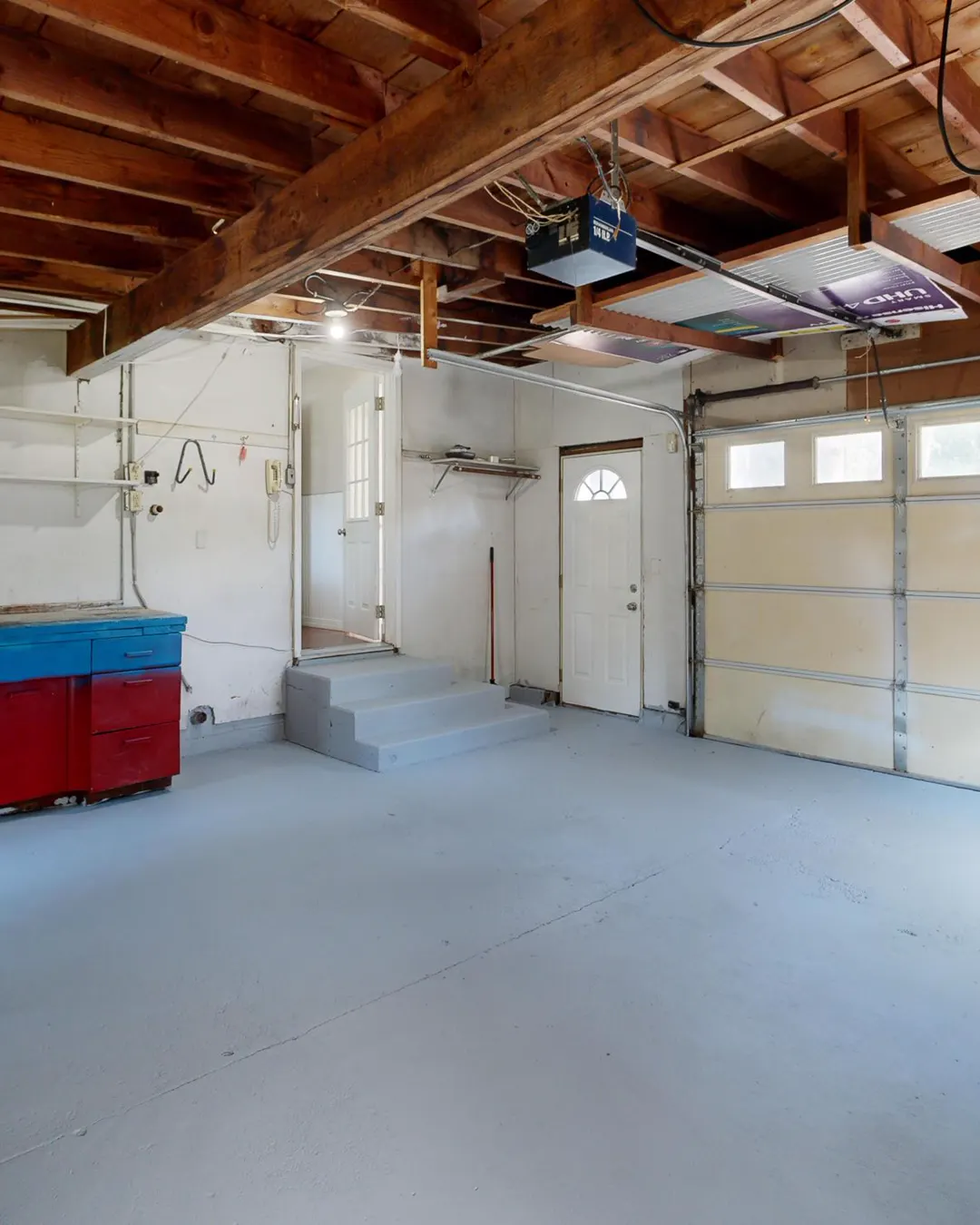 An empty garage with storage cabinets and a bare concrete floor before a conversion, garage conversion cost