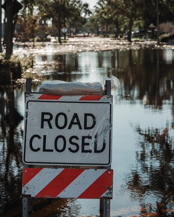 A road closed sign standing in floodwater on a street with palm trees, the case where a garage cannot become a bedroom