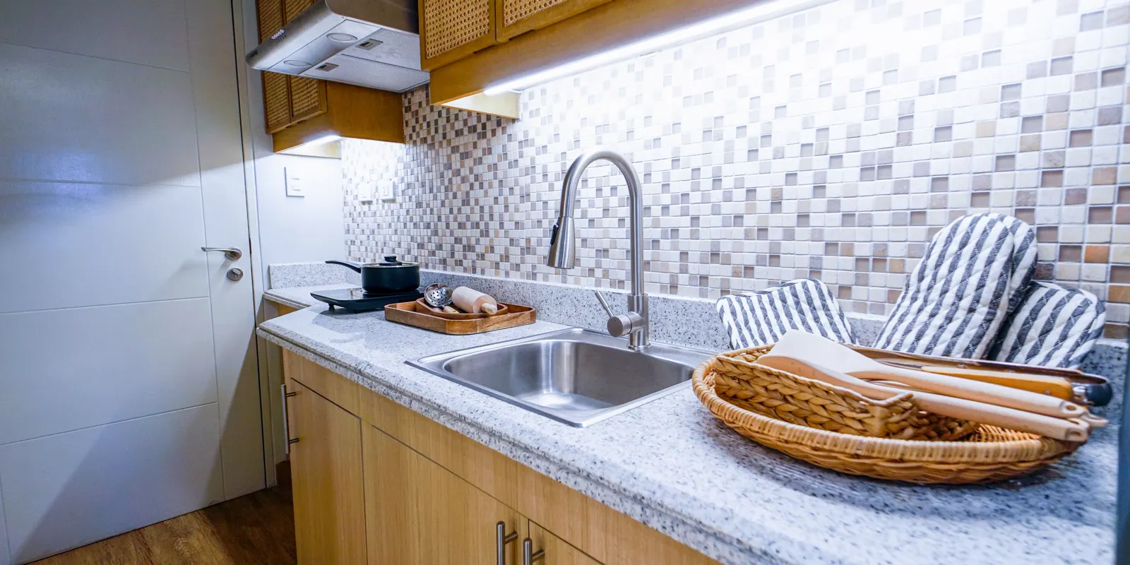A compact kitchenette with a sink, a small counter and a tile backsplash, garage to apartment conversion