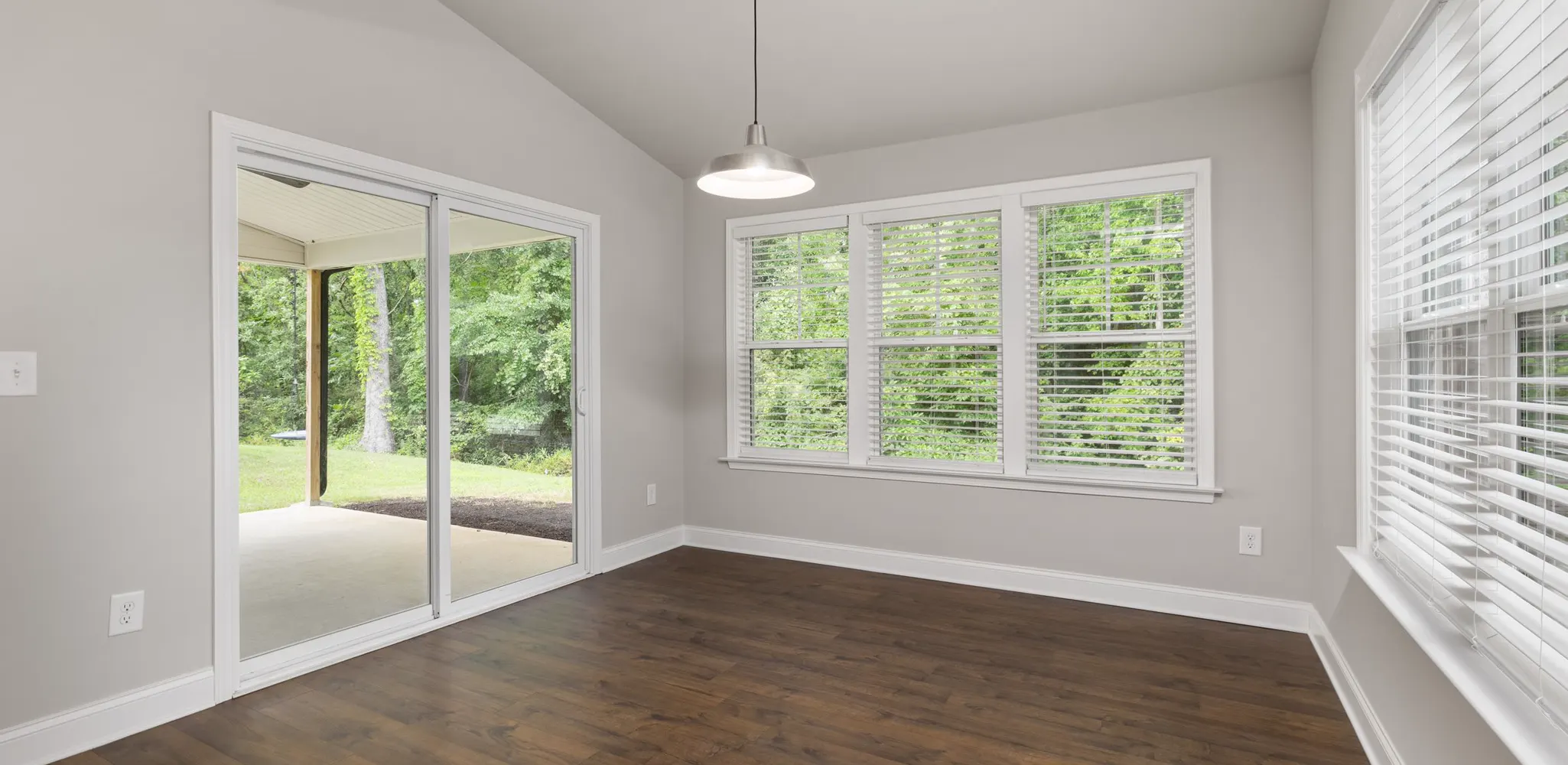 An empty new room with large windows and a wood floor, the finished side of a home addition