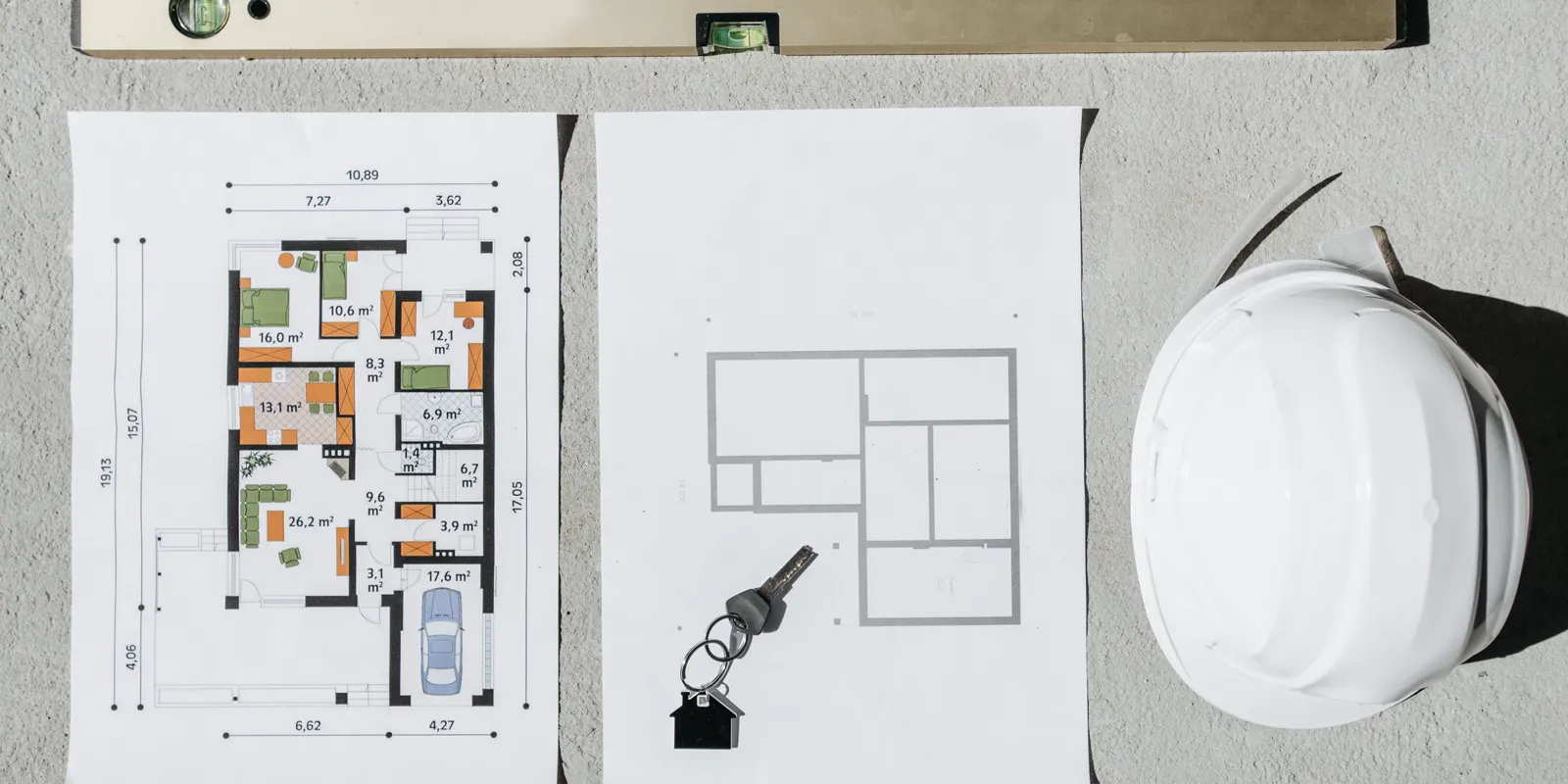 Blueprints, a spirit level and a hard hat laid out for house planning, home addition cost