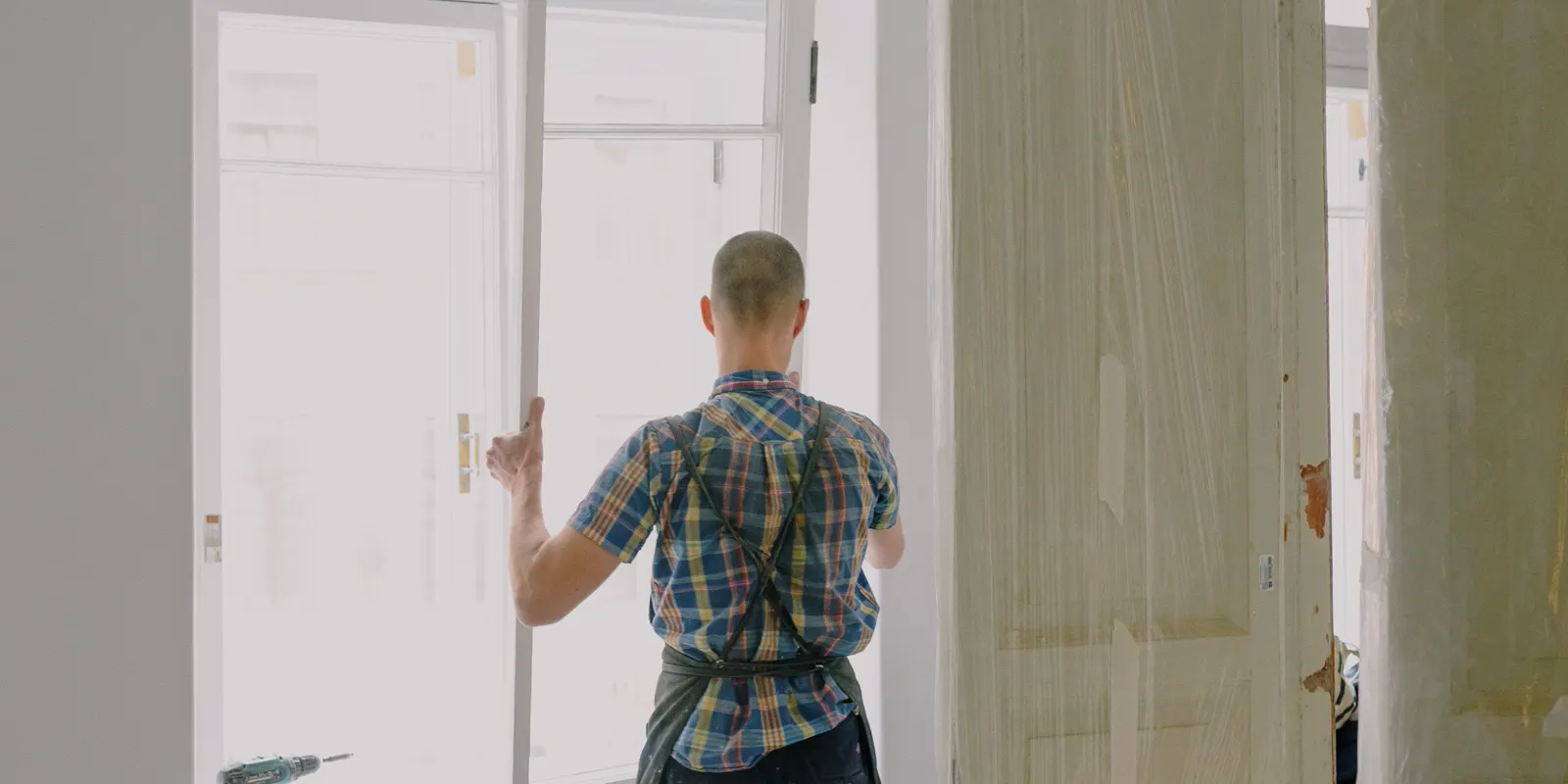A workman seen from behind installing a door, interior door replacement