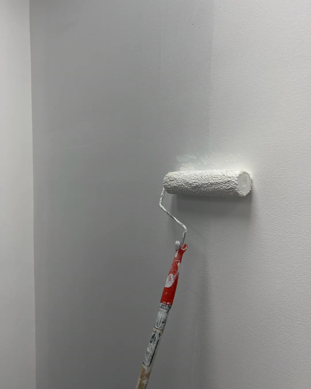 A paint roller leaving fresh white paint on an interior wall, interior painting