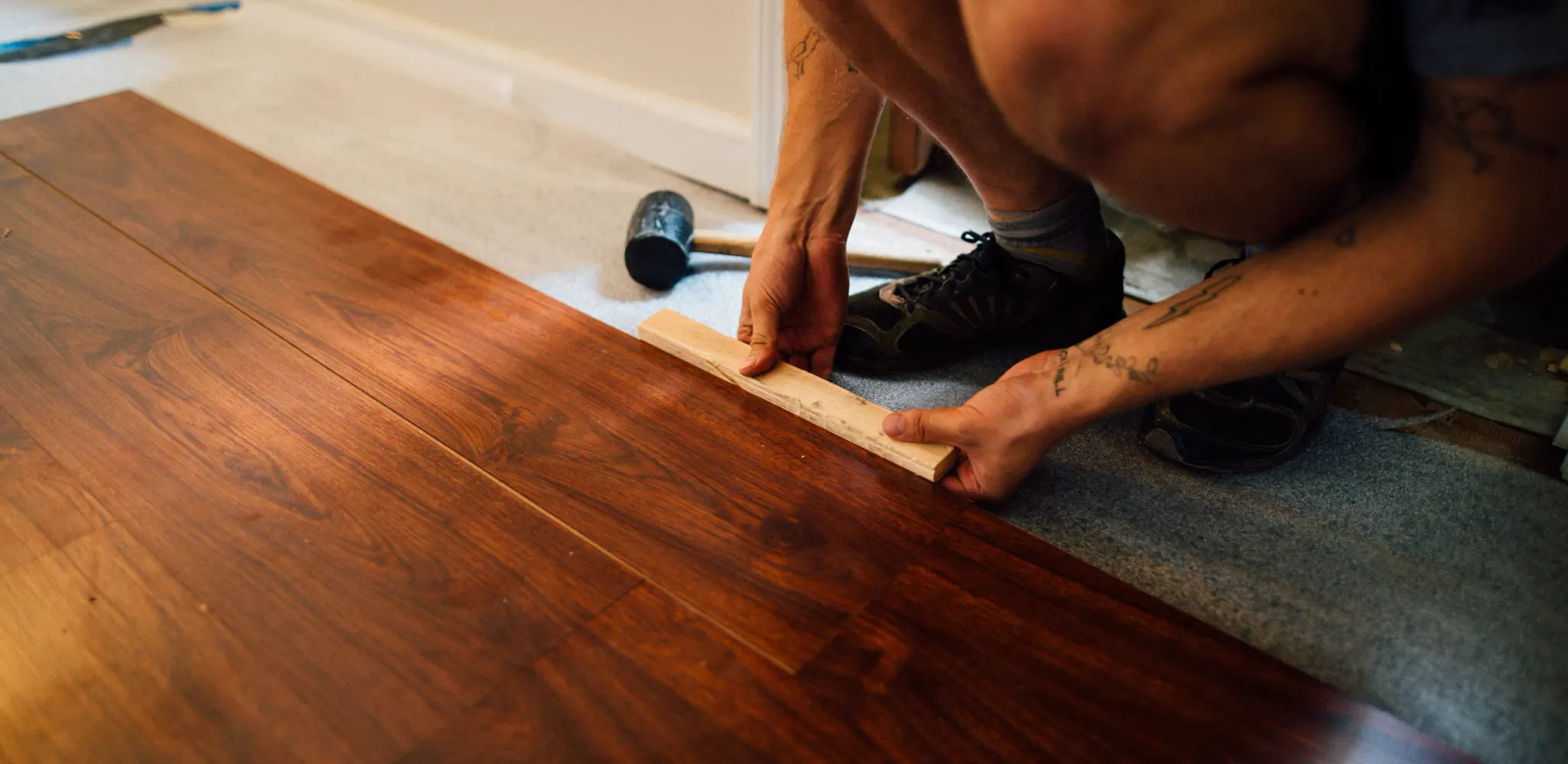 Laminate planks tapped into place with a mallet, laminate flooring installation