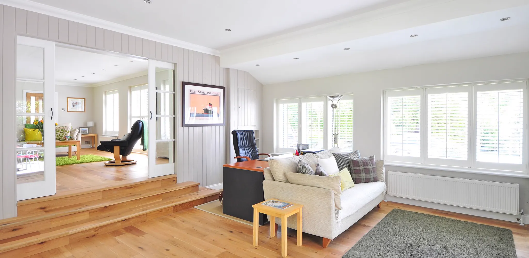 A bright living room with wooden floors and large windows, the finished side of a room addition