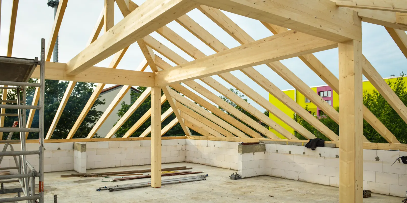 A wooden roof structure in progress with the sky showing through the rafters, room addition