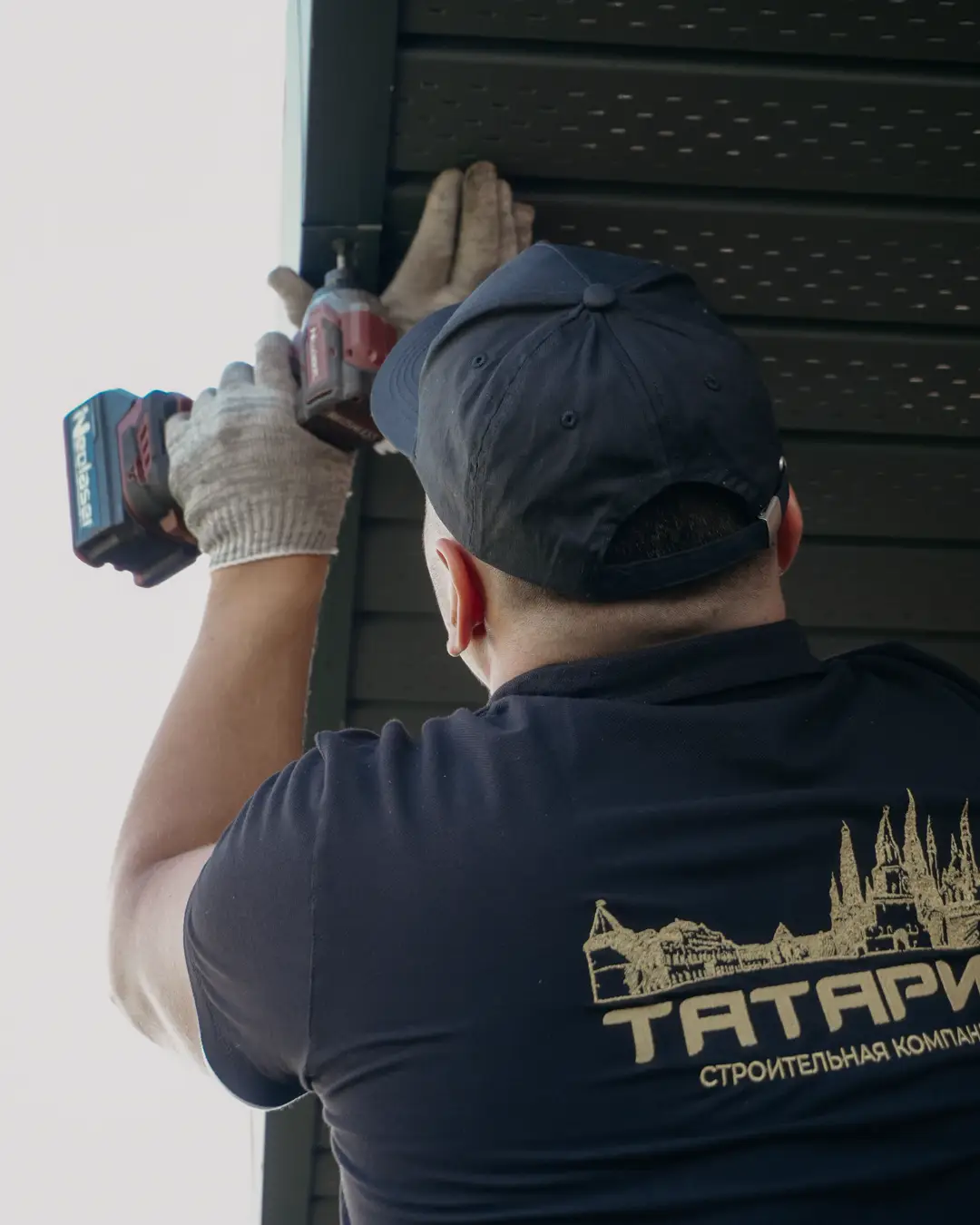 A worker installing siding boards on the exterior of a house, siding repair