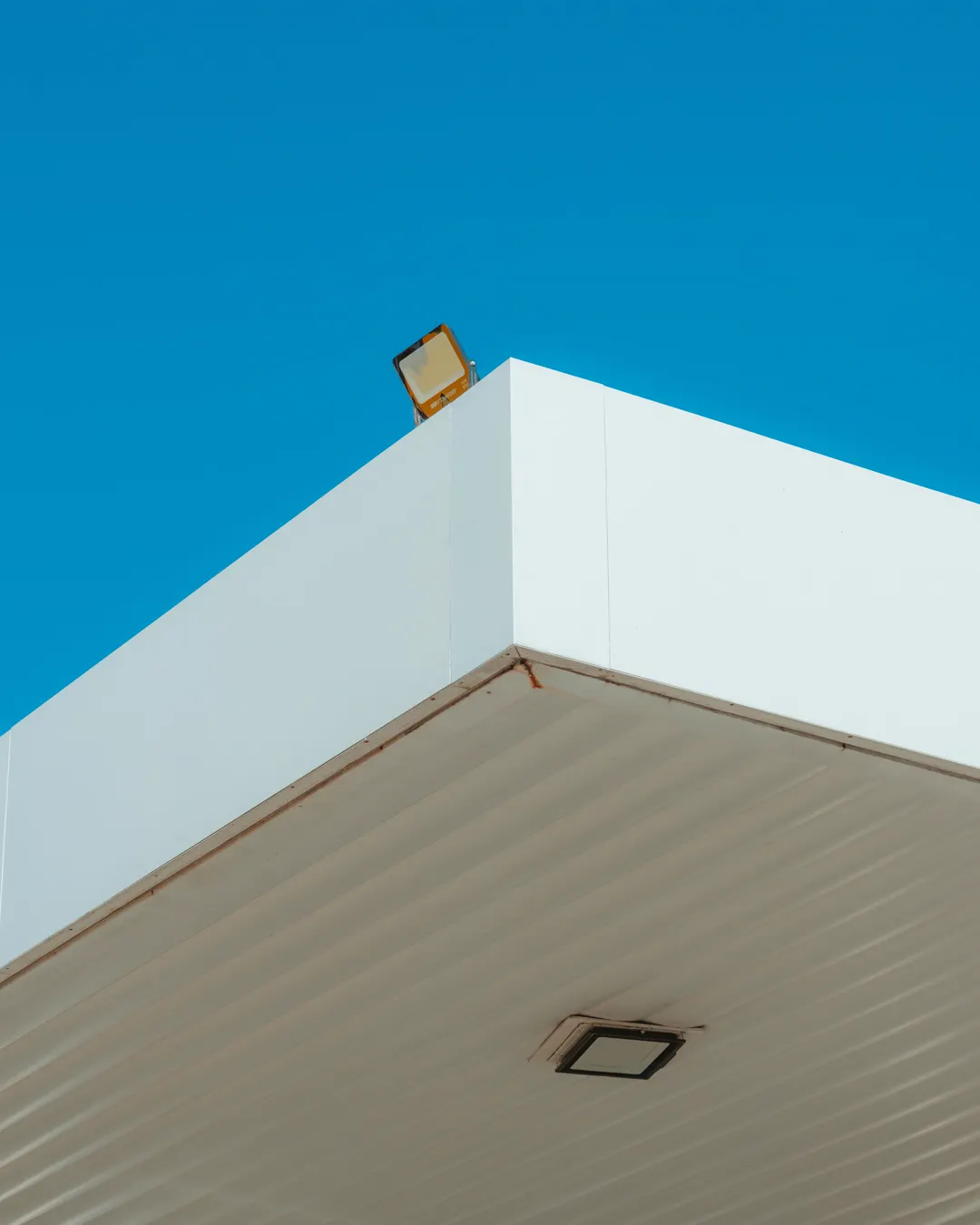 The corner of a white roof edge against a blue sky, soffit and fascia repair