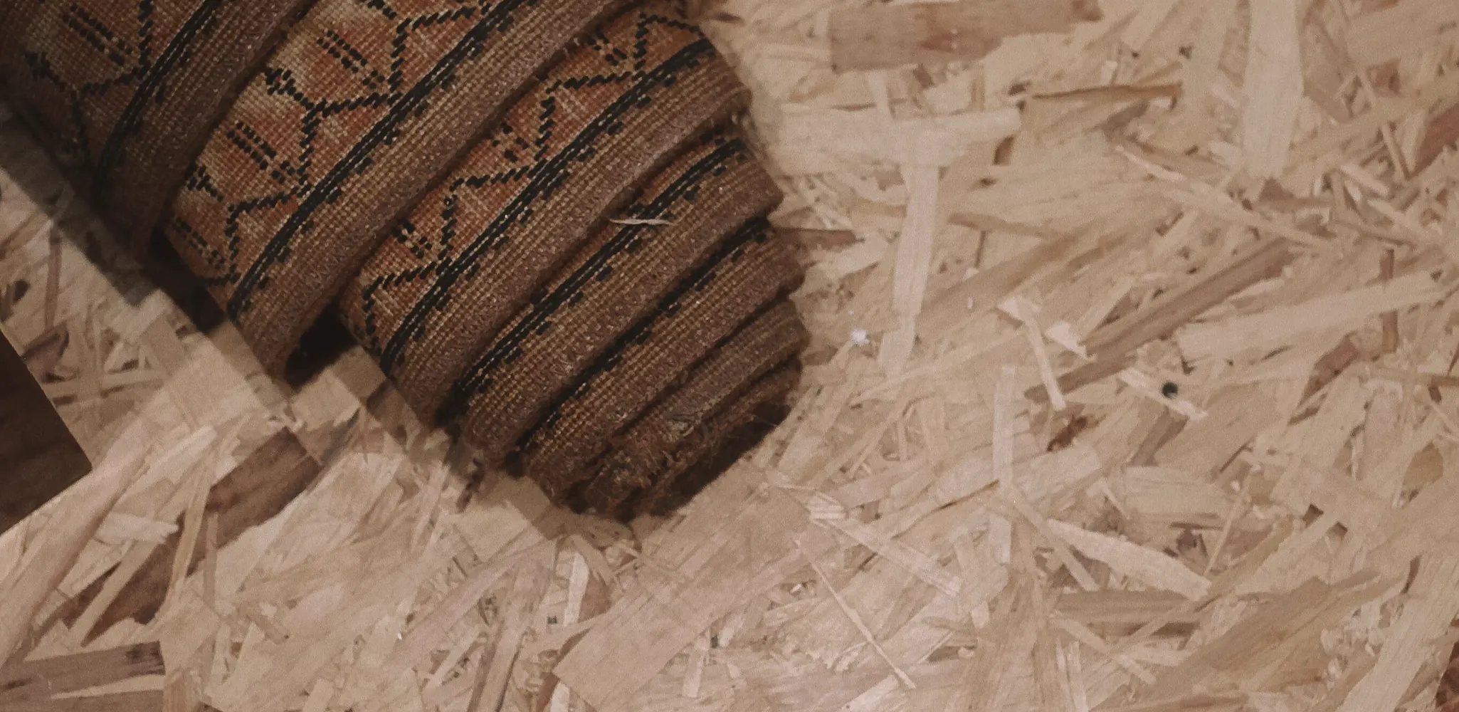 Rolled carpet on a bare wood subfloor during floor removal, subfloor repair