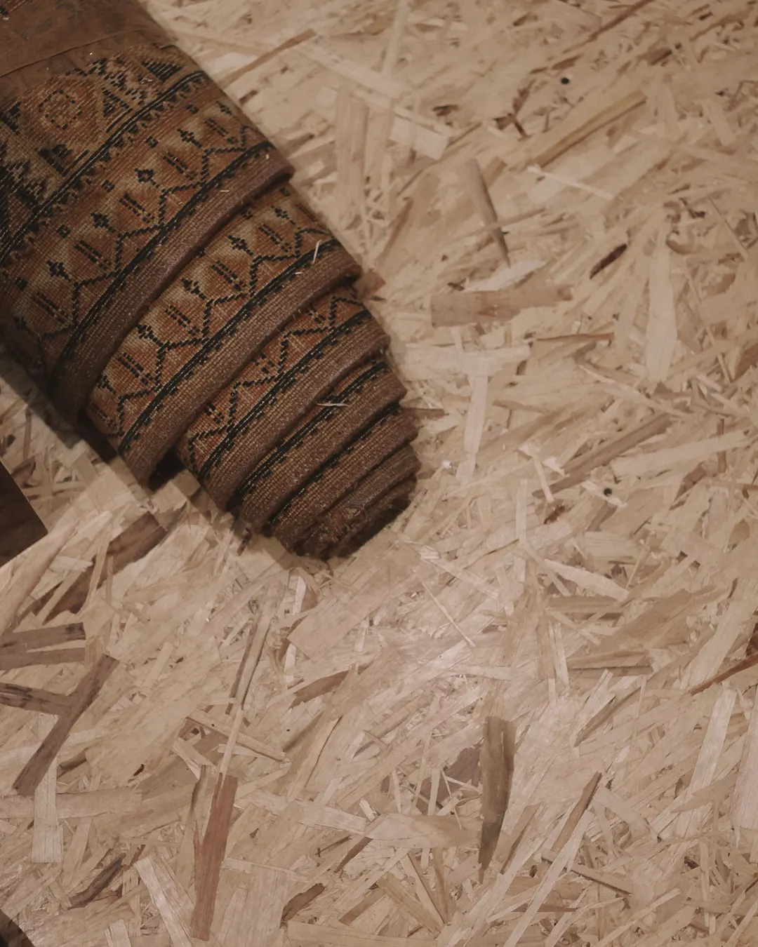 Old carpet rolled back to show the wood subfloor underneath, flooring removal and subfloor repair