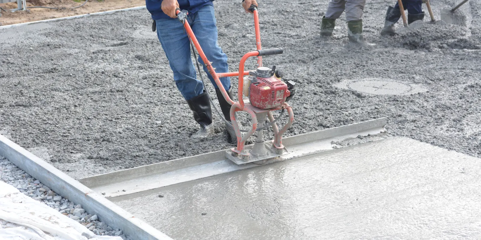 Workers leveling a freshly poured concrete slab with power tools, sunroom and Florida room